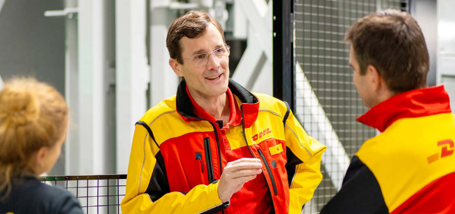 Tobias Meyer (Mitte), Vorstandsvorsitzender von DHL Group, im Gespräch mit Beschäftigten – Quelle: DHL Group Geschäftsbericht 2025, S. 4